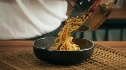Noodles Being Poured Into Bowl With Chopsticks