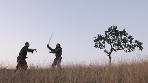Men in Costume Fight with Swords on Hillside