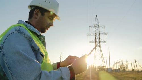 Ingenieur steht mit Strommasten auf Feld