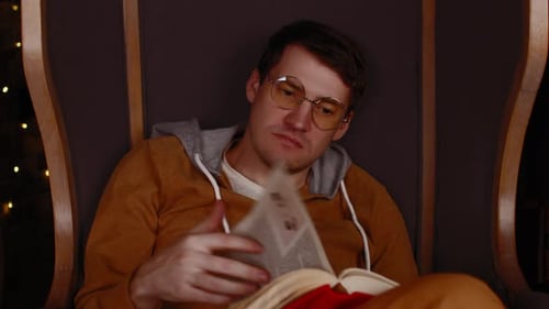 Man Reading a Book in a Chair Indoors