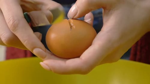 Woman Cracks Egg into Yellow Bowl Close Up