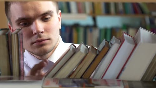 Boy Chooses a Book in the Library. Close Up, Selects the Desired