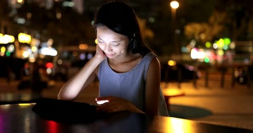 Woman Using Tablet Device at Night in City