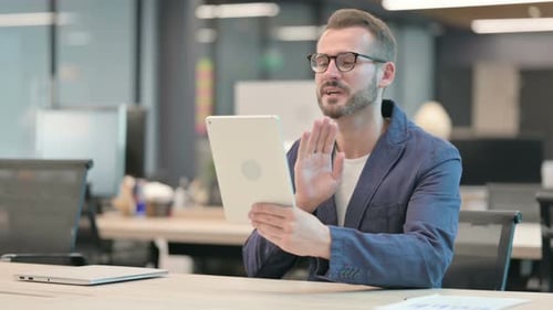 Middle Aged Businessman Making Video Call on Tablet in Office