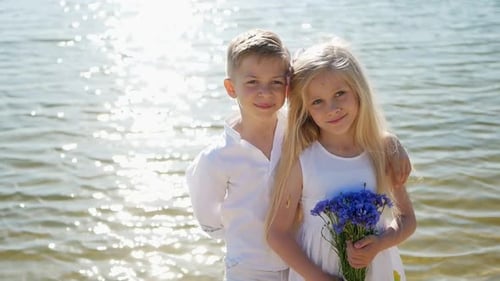 Children Smiling with Blue Flowers on Beach