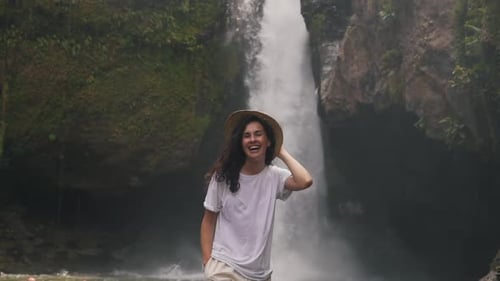 Mädchen in einem Strohhut auf einem Hintergrund eines Wasserfalls