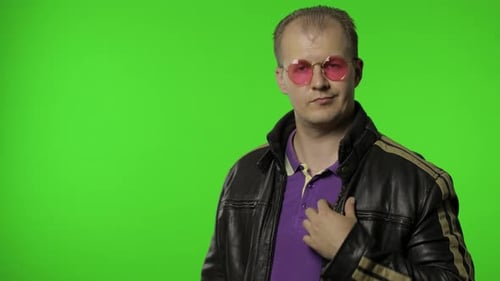 Hübscher Rocker Man mit rosa Sonnenbrille zeigt mit dem Finger auf Sie, schaut in die Kamera, trifft Wahl