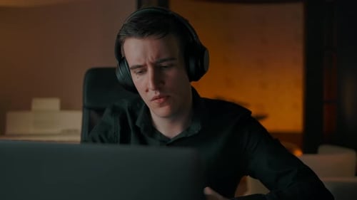 Man with Headphones Working on Computer at Night