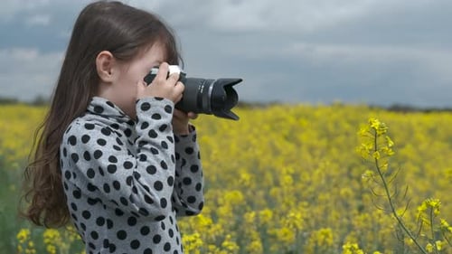 Young Girl Taking Pictures in a Yellow Field