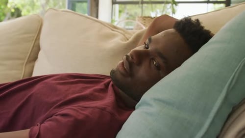 Video of relaxed african american man lying on sofa