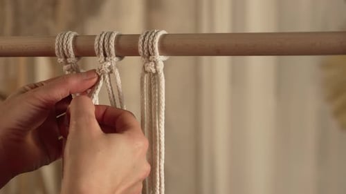 A Woman Craftsman Weaves Macrame From Light Cotton Threads in Her Home Workshop