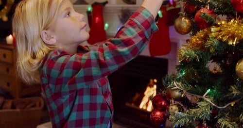 Child Decorates Christmas Tree with Festive Ornaments