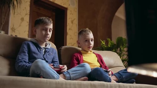 Friends or Brothers Sitting on Soft Couch and Attantivly Playing Video Games