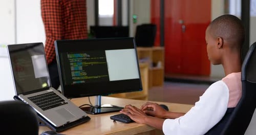 Side view of young black businesswoman working and sitting at desk in a modern office 4k