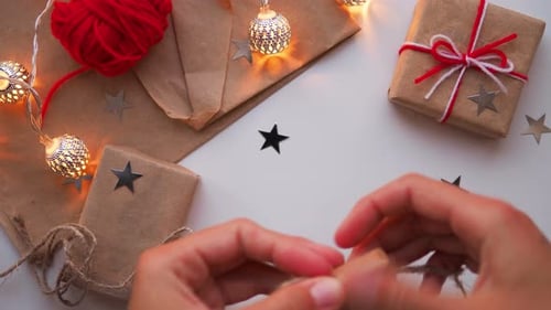 Woman Is Wrapping Present Box with Craft Paper and Red Paper Clip. Christmas and New Year Background