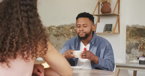 Happy diverse couple spending time together at cafe, drinking coffee and talking
