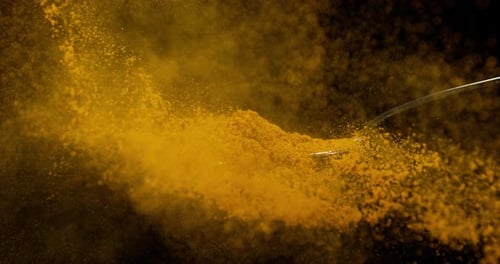 Spoon and Curry Powder falling against Black Background, Slow motion 4K