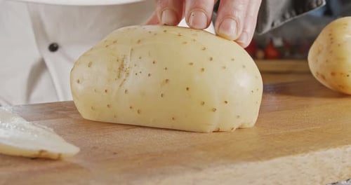 Au ralenti d'un chef tranchant une pomme de terre à l'aide d'un grand couteau bien aiguisé