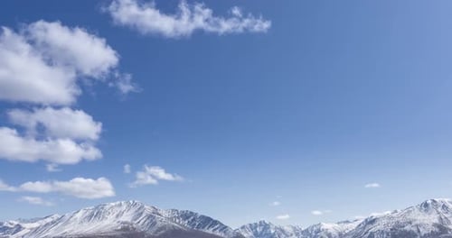 Timelapse of Sun Movement on Crystal Clear Sky with Clouds Over Snow Mountain Top. Yellow Grass at