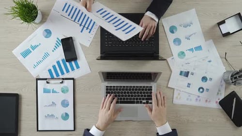 Hände von Kollegen, die an Laptops arbeiten, Unternehmensstatistiken diskutieren, Ansicht von oben