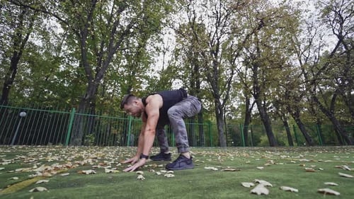 Athletic Man Doing Burpees in Urban Park