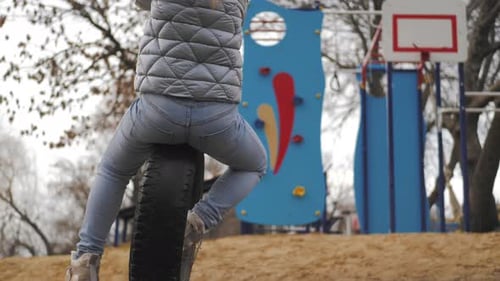 Woman Playing on a Tire Swing at Playground