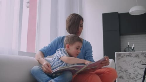 Mother and Child Reading a Book on Couch