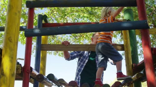 Junge klettert auf eine kleine hölzerne Hängebrücke auf dem Spielplatz