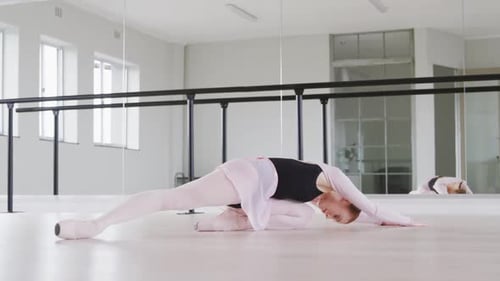 Graceful Ballerina Stretching in Bright Dance Studio