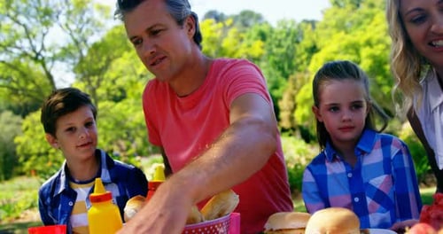 Happy family interacting with each other while having meal in park 4k