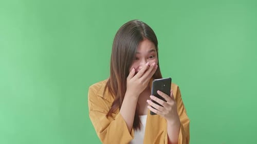 Woman Flipping Something On The Mobile Phone Becoming Surprised In The Green Screen Studio