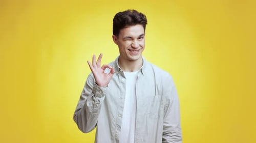 Smiling Man Makes OK Hand Gesture on Yellow