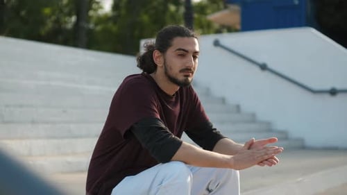 Portrait of Young Attractive Arab Man Sitting on the Stairs in Park at Sunset
