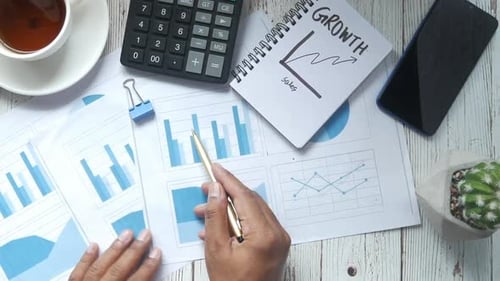 Mão de homem com caneta analisando gráfico de barras em papel