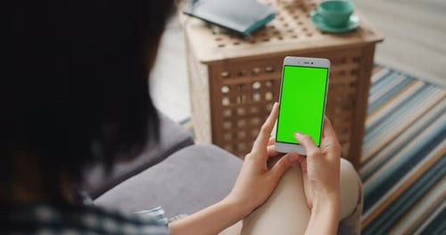 Student at Home Using Smartphone with Green Mock-up Screen Swiping