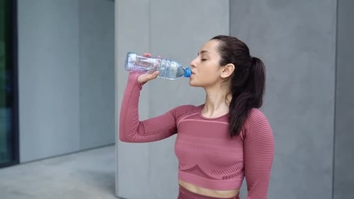 Woman Drinking Water After Exercise in City