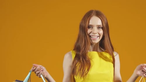 Woman Smiles with Shopping Bags on Yellow Background