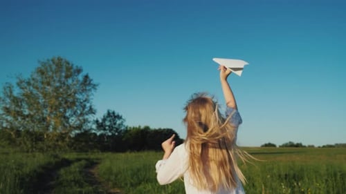 Girl Running With Paper Airplane in Sunny Field
