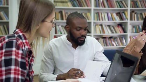 Modern Multiethnic Friends which Working Together Over their Home Task in the Library