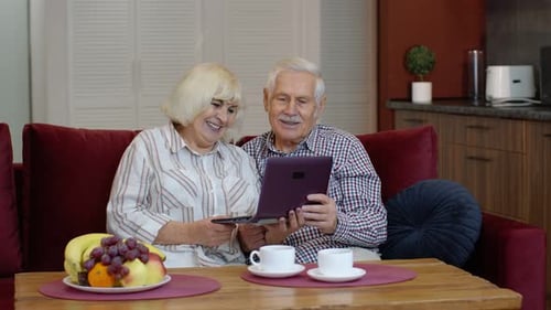 Senior Couple Relaxing on Sofa Using Laptop