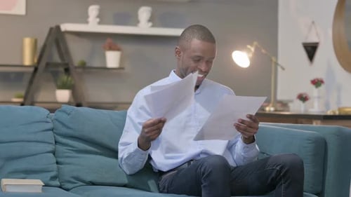 Man Reviewing Documents While Sitting on Couch