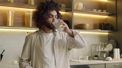 Arabian Man Enjoys Drinking Milk in Glass in Kitchen at Home