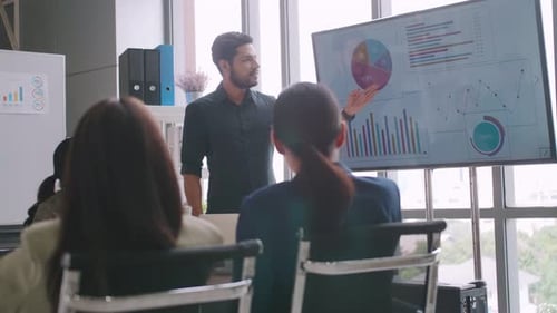 Man Presents Business Charts in Modern Meeting
