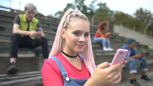 Four Young Adults Using Mobile Phones on Bleachers
