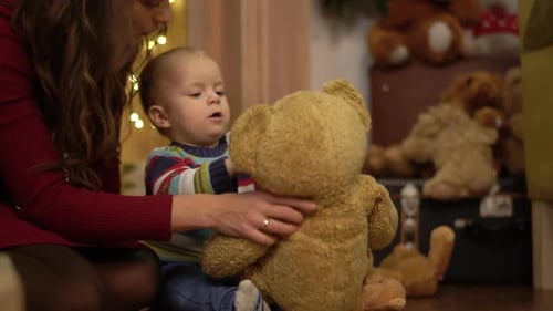 Little Cute Child Playing with Big Teddy Bear at Home
