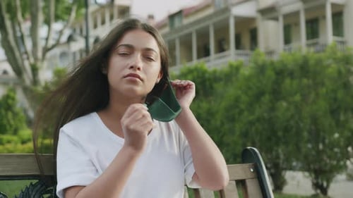 Young Woman Removes Mask and Smiles in Park