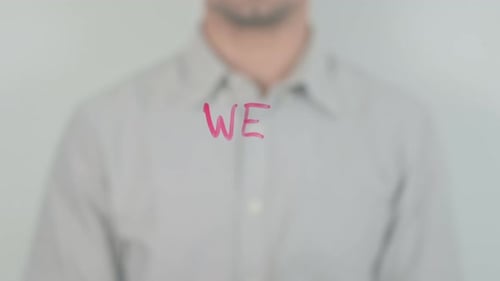 Hand Writes 'WE' on Transparent Screen with Marker