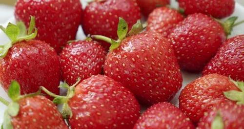 Fresas frescas, girando lentamente. Fondo blanco rotado