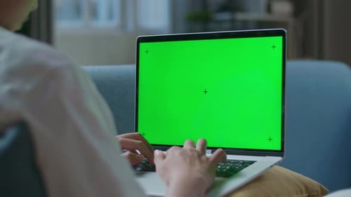 Close Up Of A Man Typing On Green Screen Laptop While Lying On Sofa In The Living Room