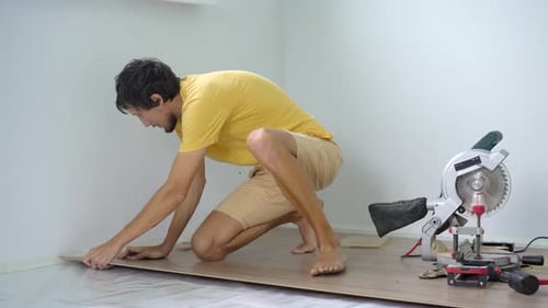 Man Installing Laminate Wood Flooring in Home